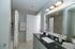 Elegant bathroom with modern fixtures, featuring a sleek black countertop, spacious mirror, and soft ambient lighting.