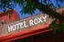 Charming hotel sign on rustic brick facade framed by vibrant green leaves.