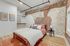 Cozy bedroom with exposed brick wall, modern open shelving, and warm decor for a contemporary urban vibe.