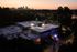 Charming rooftop view of a vibrant urban building at sunset, surrounded by lush greenery and a stunning city skyline.
