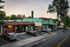Charming urban street scene at sunset featuring colorful storefronts, inviting outdoor seating, and lush trees, perfect for dining and shopping.