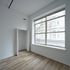 Bright and spacious room with elegant wood flooring and large windows, perfect for natural light and city views.