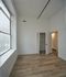 Bright and airy bedroom with modern wood flooring and a spacious closet, featuring a large window offering a scenic city view.