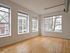 Bright corner room with large windows and charming city view, featuring elegant wooden floors and modern exposed ductwork.