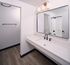 Modern bathroom with sleek vanity, elegant black fixtures, spacious mirror, and stylish lighting.