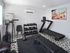 Modern gym with a treadmill, exercise bike, and a set of dumbbells on stylish patterned flooring.