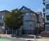 Charming blue two-story building with large windows and a beautiful tree in the front yard, nestled in an inviting urban neighborhood.