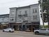 Charming urban building with vibrant storefronts, including a coffee roaster and beer garden, set in a bustling neighborhood.