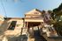 Charming Victorian-style home with elegant columns and large bay windows, basking in sunlight against a clear blue sky.
