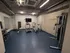 Modern fitness room featuring a treadmill, exercise bikes, and weight bench in a sleek urban setting.