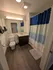 Modern bathroom featuring elegant dark wood flooring, sleek vanity with under-counter storage, and inviting shower with a vibrant blue and white curtain.