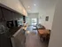 Modern open-concept apartment kitchen and living area with sleek black cabinets, cozy sofa, and inviting dining space bathed in natural light.