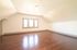 Bright and spacious attic room with sleek hardwood floors, featuring a trio of modern windows for natural light.
