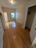 Bright bedroom with polished hardwood floors, ample natural light from large window, and spacious closet.