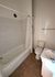 Charming bathroom with elegant tiled flooring, featuring a cozy bathtub, modern sink, and convenient storage space.