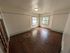 Charming room with elegant hardwood floors, ample natural light from large windows, and classic wooden door.