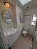 Charming bathroom with elegant oval mirror, stylish wall-mounted sink, and skylight providing natural light.