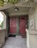 Charming dual-entryway with vibrant red doors, welcoming mats, and lush hanging greenery, exuding a warm and inviting entrance.