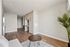 Modern apartment interior with sleek hardwood flooring, stylish built-in cabinets, and cozy seating area accented by a decorative plant.