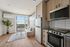 Bright and modern apartment kitchen with stainless steel appliances, cozy seating area, and large windows offering stunning city views.