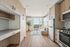 Modern apartment interior with sleek wood cabinetry, integrated kitchen appliances, and a cozy seating area with panoramic city views.