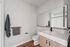 Modern bathroom with sleek vanity, large mirror, and elegant fixtures, showcasing minimalist design and functionality.