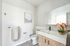 Bright and elegant bathroom with modern fixtures, large mirror, and a beautiful floral arrangement.