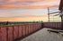 Breathtaking rooftop terrace under construction with panoramic sunset views over a vibrant city landscape.