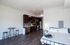 Modern studio apartment with sleek open kitchen, stylish dark cabinets, cozy bed, and rustic wood flooring, perfect for comfortable living.