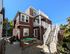 Charming multi-level brownstone apartment with white trim, featuring spacious outdoor stairs and cozy patio area, bathed in bright sunlight.