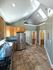 Bright kitchen with vaulted ceilings, skylights, stainless steel appliances, and elegant tile flooring, leading to a cozy loft area.