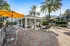 Inviting outdoor seating area with modern patio furniture, vibrant yellow umbrellas, and lush palm trees, perfect for relaxation and entertaining.