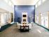 Inviting clubhouse with a grand, open-concept lounge featuring a stone fireplace, modern decor, plush seating, and ample natural light from large windows.