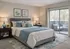 Cozy and elegant bedroom featuring a plush bed with blue accents, stylish bedside tables, and a serene balcony view perfect for relaxation.