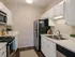 Modern kitchen with sleek stainless steel appliances, white cabinetry, and elegant wood flooring.