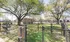 Charming fenced dog park with lush greenery and shaded trees, featuring seating areas and playful space for pets.
