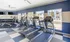 Modern fitness center with state-of-the-art treadmills, exercise bikes, and weight equipment in a bright, inviting space with large windows overlooking the pool area.