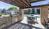 Upscale outdoor patio with built-in grill and dining area overlooking a serene swimming pool, perfect for entertaining.