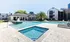 Luxurious apartment complex with a sparkling pool, hot tub, and modern clubhouse, surrounded by lush landscaping and contemporary architecture.