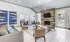Chic apartment lounge with modern decor, featuring cozy seating, abstract artwork, a stylish wood-paneled fireplace, and ample natural light.