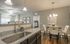 Elegant apartment interior featuring a modern kitchen with granite countertops, stylish dining area, and a glimpse into a cozy bedroom.