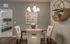Elegant dining area with contemporary furniture, artistic wall decor, and a glimpse of a cozy bedroom in the background.