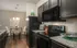 Contemporary kitchen and dining area with sleek dark cabinets, granite countertops, and elegant lighting, perfect for modern living.