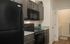Modern kitchen with sleek black appliances, elegant gray cabinets, and stylish granite countertops, leading to a convenient laundry area.