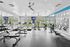 Modern, sunlit fitness center with state-of-the-art equipment, large mirrors, and scenic outdoor views ideal for health and wellness.