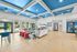 Vibrant and spacious living area with modern decor, colorful accents, and large windows overlooking lush greenery. Ideal for relaxation and entertaining.