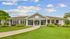 Elegant clubhouse facade framed by lush greenery and vibrant landscaping under a clear blue sky.