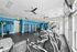 Modern fitness center with state-of-the-art equipment, vibrant blue walls, and ample natural light.