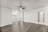 Spacious and modern living area with beautiful hardwood floors, abundant natural light from large windows, and a ceiling fan for added comfort.