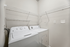 Bright laundry room with modern washer and dryer, featuring ample shelving for storage.